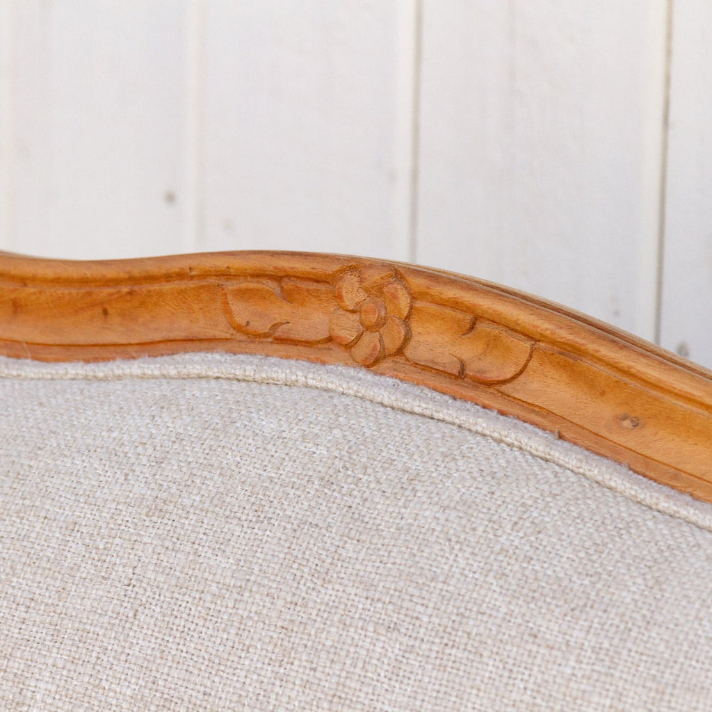 Close-up of a wooden chair with a floral design against a white paneled wall.