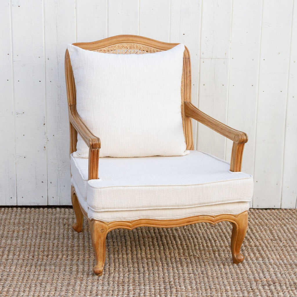 Wooden armchair with white cushion against a white wooden panel background